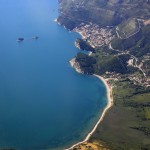 Petrovac: Aerial view of the coast with the town, centre and Budva in the distance, top